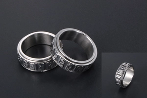 Detailed macro view of rotatable stainless steel ring with embossed mantra characters