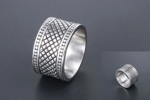 Vue détaillée d'une bague large en acier titane avec motif de grille diamantée