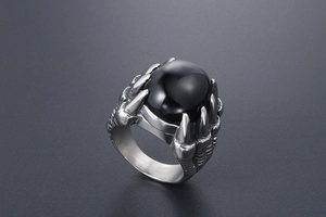 Gros plan de la bague griffe de dragon gothique avec pierre noire et détails d'écailles