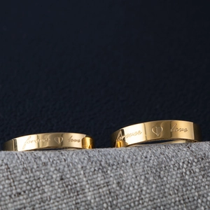 Macro detail of polished gold rings with forever love engraving and heart symbol