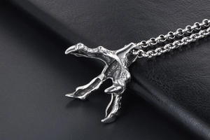 Close-up of a punk-style silver dragon claw pendant on a stainless steel link chain