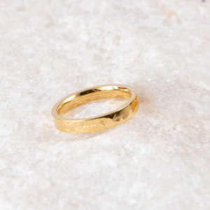 Close-up of golden stainless steel ring with engraved heart pattern and love text