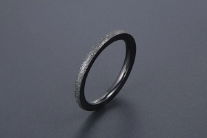 Close-up of minimalist black frosted titanium steel ring with sparkling sand finish