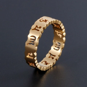 Bague mantra ajourée dorée en acier inoxydable brossé sur fond noir élégant