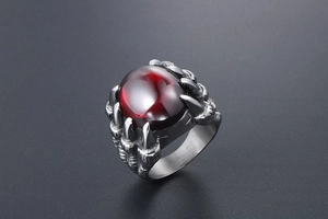 Gros plan d'une bague griffe de dragon vintage pour homme avec pierre rouge et métal brossé
