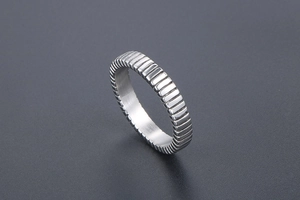 Macro detail of silver titanium steel ring with textured industrial groove patterns