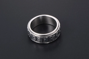 Close-up of rotatable titanium steel ring with embossed mantra on a gray background