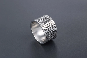 Vue macro de la bague large en acier argenté avec texture grille et bords perlés