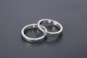 Detailed close-up of titanium steel rings with textured vertical stripe industrial design