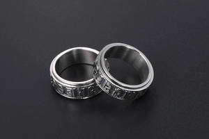 Detail of spinning stainless steel ring with embossed Sanskrit mantra on silver finish