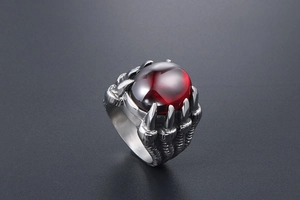 Détail d'une bague griffe de dragon vintage avec une grande pierre précieuse rouge gothique