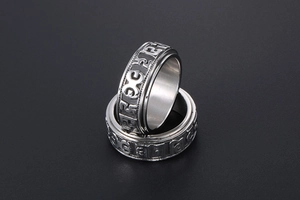 Macro shot of silver rotatable mantra rings with embossed Tibetan scriptures on black background