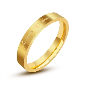 Detail of golden stainless steel ring band featuring engraved forever love text and heart
