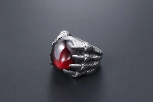 Détail d'une bague griffe de dragon gothique avec une grande pierre rouge ovale