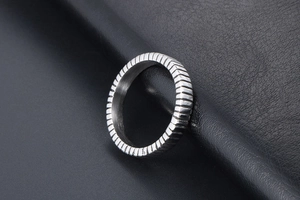 Detailed close-up of a silver titanium steel ring with industrial grooved textures