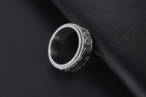 Detail of rotating silver stainless steel ring with embossed vintage relief symbols