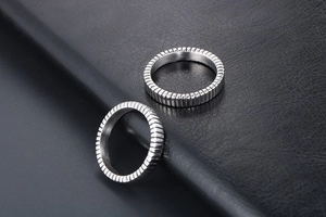 Macro shot of two silver titanium steel rings with vertical striped texture on black leather