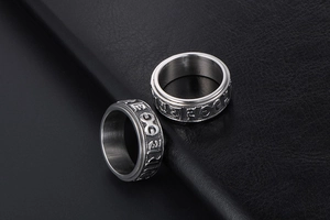 Detail of spinning stainless steel rings with engraved Six-Syllable Mantra on leather