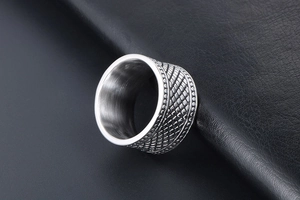 Vue macro d'une bague large argentée avec motif quadrillé vintage et métal brossé