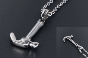 Macro detail of polished stainless steel mini hammer pendant on a cross chain necklace