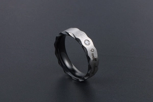 Detailed shot of dark gray brushed steel ring with I will always engraving and zircon