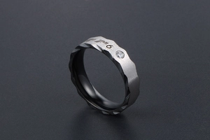 Macro shot of brushed titanium ring with engraved pledge and small zircon stone