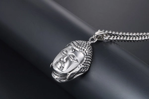 Detalle de un colgante de cabeza de Buda plateado con cadena de bolas texturizada
