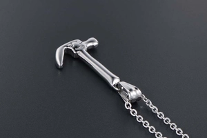 Macro detail of polished stainless steel silver hammer pendant with sleek mirror finish