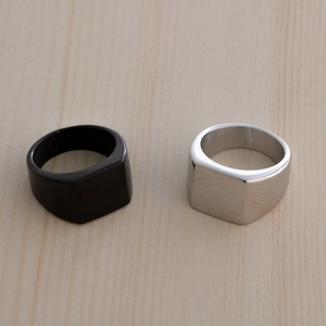 Minimalist square signet rings in black and silver steel on a wooden surface