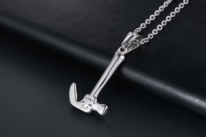 Macro shot of silver hammer pendant on black leather showing polished steel craftsmanship