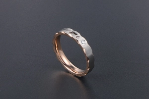 Detail of wave-edged bicolor titanium ring with micro-set zircon and engraved text