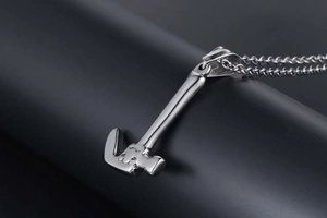 Close-up of a mini stainless steel hammer pendant necklace on a sleek black stand