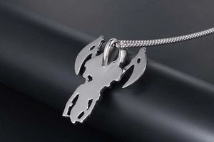 Macro shot of polished silver steel reaper pendant with sharp edges on a dark display stand