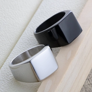 Macro shot of black and silver square signet rings on a textured white leather background