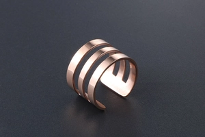 Detailed macro shot of a three-layered rose gold open ring with polished finish