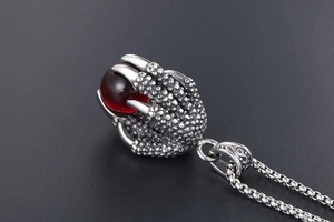 Macro shot of retro stainless steel dragon claw pendant with deep red gemstone