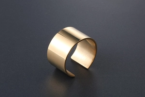 Close-up of wide gold-plated stainless steel ring with polished finish and open design