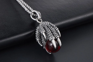 Macro detail of dragon claw necklace with red stone and stainless steel chain link