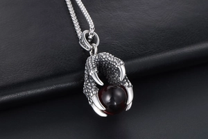 Macro detail of retro dragon claw pendant with deep red gemstone and aged steel texture