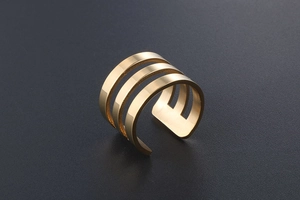 Detailed close-up of a three-layer hollow rose gold ring on a textured grey surface