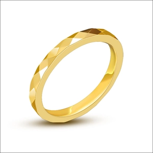 Dettaglio macro di anello in acciaio dorato con superficie a sfaccettature geometriche