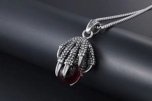 Macro view of gothic dragon claw pendant with red gemstone on stainless steel chain