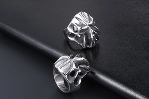 Macro shot of silver gothic skull rings with skeleton claws on black leather surface