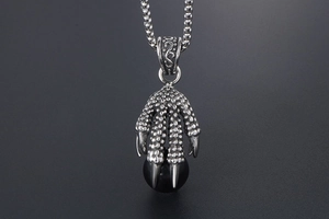 Detailed close-up of retro stainless steel dragon claw pendant holding a black bead charm