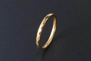 Vista macro di un anello dorato minimalista con dettagli geometrici sfaccettati