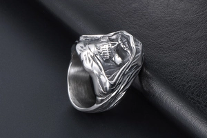 Detail shot of punk gothic skull ring in matte titanium steel on black leather background