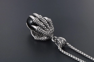 Macro detail of stainless steel dragon claw pendant clutching a black onyx stone sphere