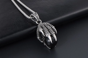 Macro detail of gothic stainless steel dragon claw pendant with black onyx bead