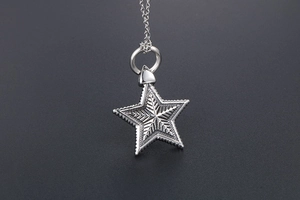 Close-up of vintage engraved star pendant with detailed texture on steel necklace