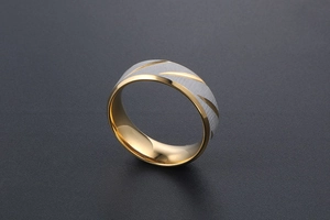 Detail of brushed metal ring featuring gold diagonal grooves and a polished inner band